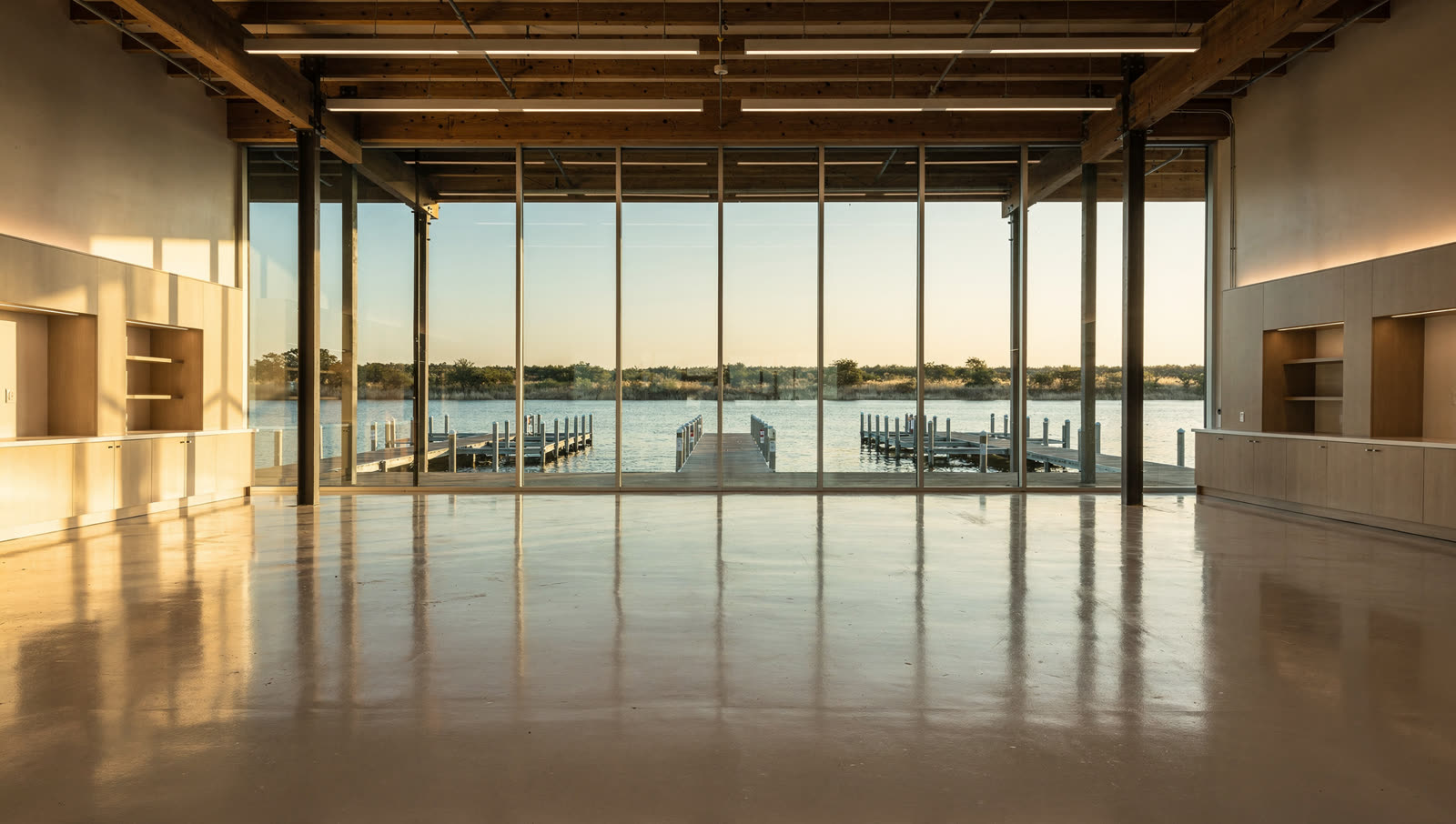 A finished commercial floor in a lakeside retail pavilion near a large North Texas reservoir, open glazed front, water and boat docks beyond