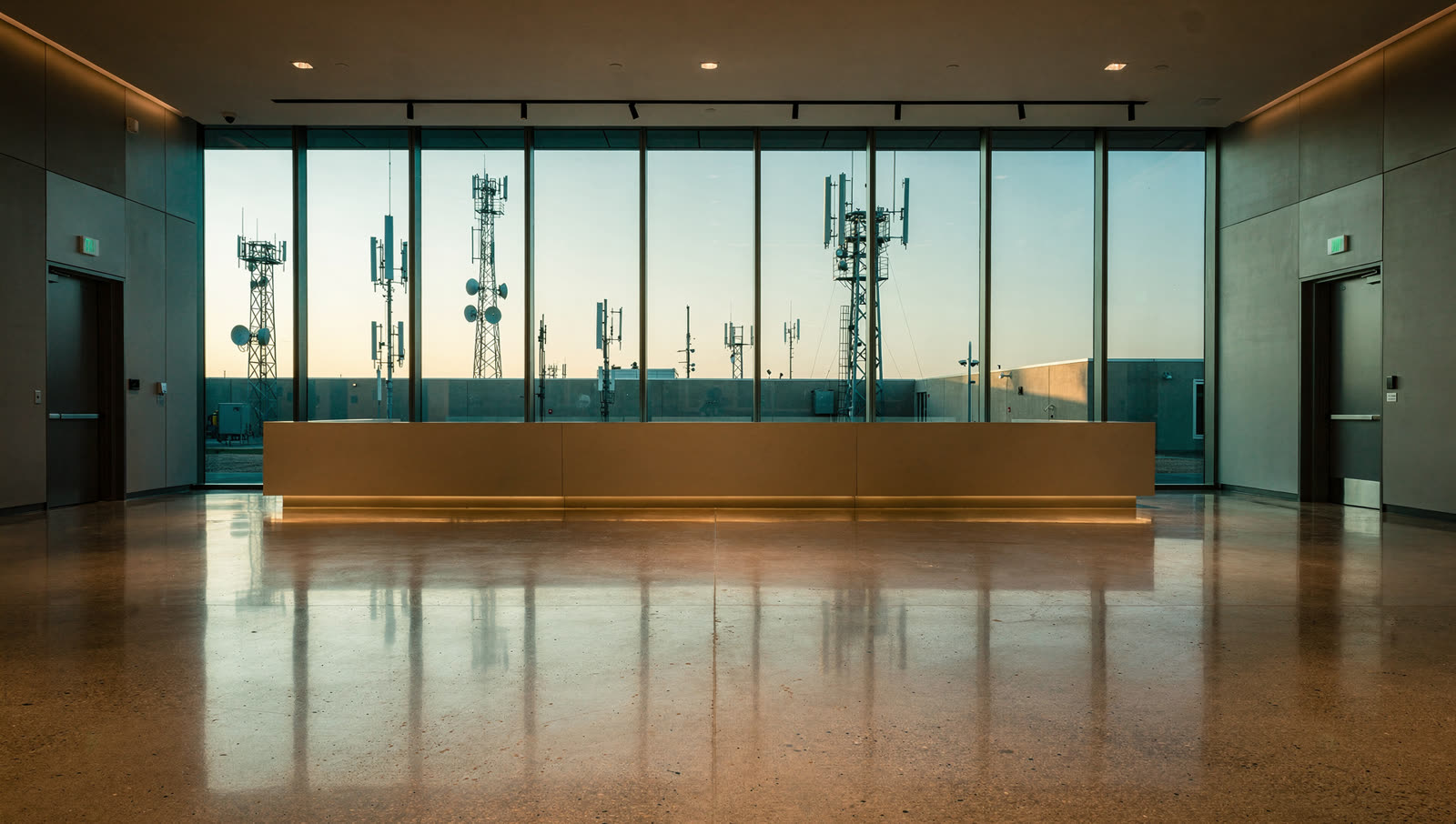 A finished commercial floor in a telecom research building lobby in the North Texas technology corridor, long low reception plane, glass and antenna masts beyond