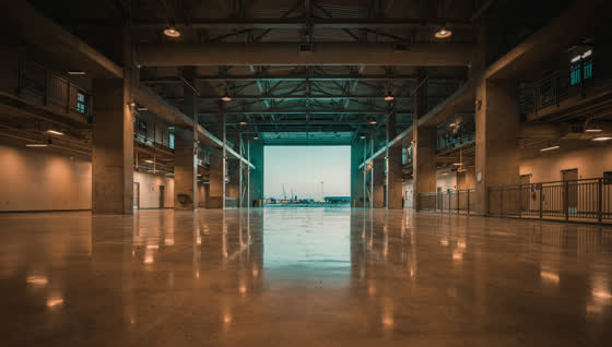 A finished commercial floor in a stadium concourse in the North Texas entertainment district, heavy columns, evening sky through the open portal