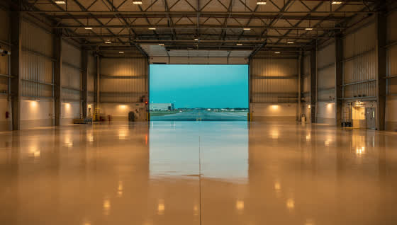 A finished commercial floor in a aviation maintenance hangar between Dallas and Fort Worth, enormous door open to a taxiway at dusk